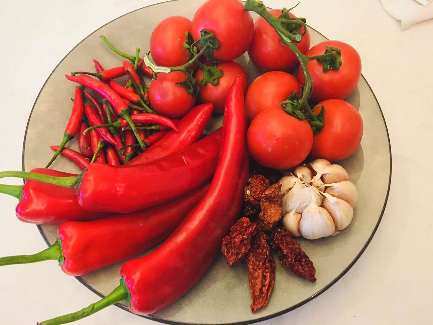 Fresh ingredients: red peppers, tomatoes, dried ghost peppers, and garlic